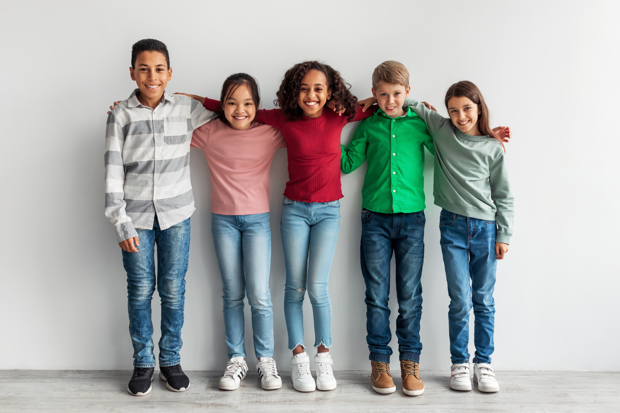 Group of Happy Diverse Preteen Children Embracing over Gray Background